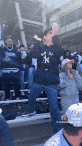 a man wearing a new york yankees shirt is holding a hot dog in his hand