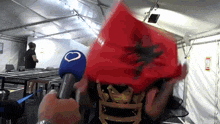 a person covering their face with a red flag and holding a microphone with a heart on it