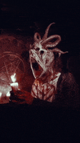 a dark room with candles and a pentagram in the background