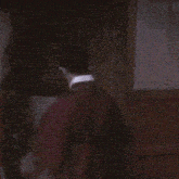 a man in a red robe is standing in front of a window