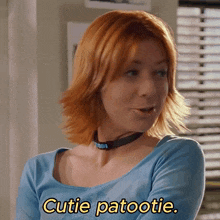 a woman with red hair is wearing a blue shirt and says cutie patootie