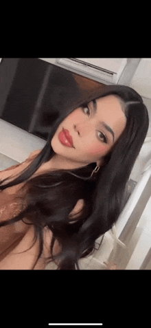 a woman with long black hair and red lipstick is taking a selfie .