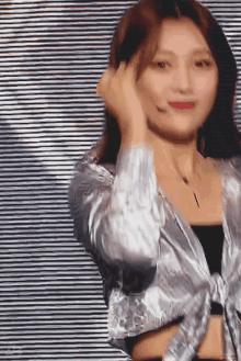 a woman wearing a silver jacket and a black top is dancing on a stage