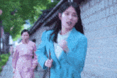 a woman in a blue jacket is running down a street