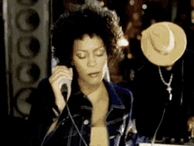 a woman is singing into a microphone while a man is holding a hat .