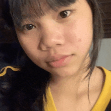a close up of a young woman 's face with a yellow shirt on