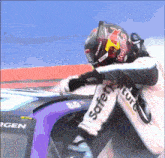 a man wearing a red bull helmet is sitting in a race car