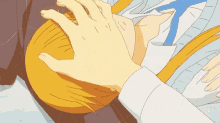 a person is touching another person 's head with their hand .