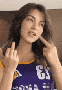 a woman in a purple jersey is giving the middle finger to the camera .
