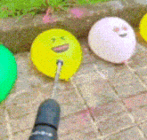 a yellow balloon with a face on it is being drilled with a drill