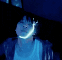 a close up of a person 's face in a dark room with blue lights behind them .