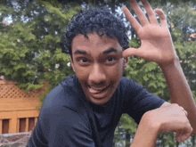 a young man with curly hair is making a funny face with his hand