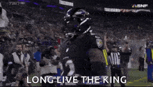 a football player is standing on a field with the words `` long live the king '' written above him .