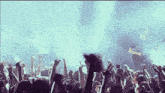 a crowd of people at a concert with their hands up