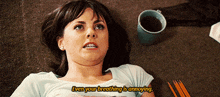 a woman is laying on the floor with a cup of coffee and pencils and says even your breathing is annoying