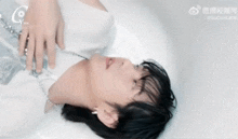 a man is laying in a bathtub with chinese writing on the bottom right