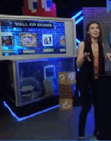a woman standing in front of a wall of shame display