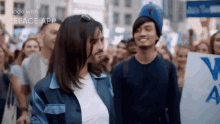 a man and a woman are standing next to each other on a crowded street .