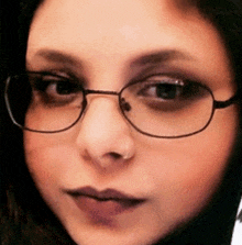 a woman wearing glasses and a nose ring looks at the camera
