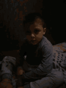 a young boy is laying on his back on a bed in a dark room .