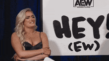 a woman is sitting in front of a sign that says hey ( ew )