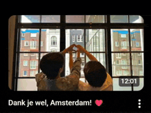 two people are making a heart shape with their hands in front of a window with the time 12:01
