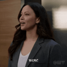 a woman in a suit says wow in front of a door