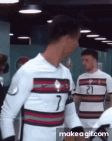 a soccer player wearing a number 7 jersey is standing in a room .