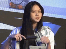 a woman is holding a hair straightener in her hand while standing on a stage .
