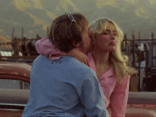 a woman in a pink shirt is kissing a man in a blue shirt with a butterfly on the back
