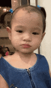 a little girl wearing a blue denim dress looks at the camera