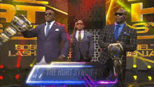 three men in suits and ties stand in front of a sign that says the hurt syndicate