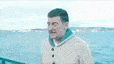 a man in a sweater is standing on a pier overlooking the water .