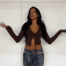 a woman is standing in front of a white wall with her arms outstretched .