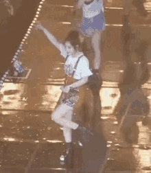 a woman is standing on a wet stage holding a microphone