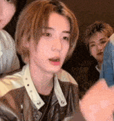 a close up of a person wearing a leather jacket and looking at the camera .