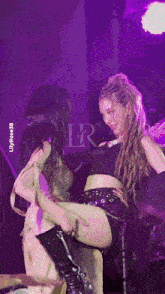 two women are dancing on a stage with the letters lr on the bottom left