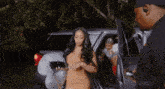 a woman in a dress is getting out of a car with a zeus logo on the side