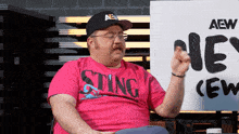 a man wearing a pink shirt that says sting