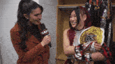 a woman holding a wrestling championship is being interviewed by a woman with a microphone that says raw