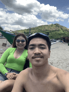 a man and a woman pose for a picture on a beach