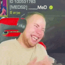 a man wearing headphones is laughing in front of a sign that says meds2 .