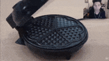 a heart shaped waffle maker with a man in the background behind it