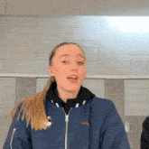 a girl wearing a blue jacket with a sticker on it that says ' slazenger ' on it