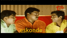 three men are sitting on a red couch and one of them is saying eskonde