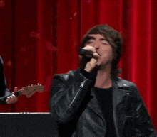 a man singing into a microphone with his arms in the air