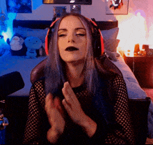a woman with blue hair wearing headphones and a black shirt