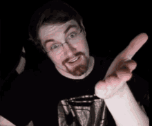 a man with glasses and a beard holds his hand up to his face