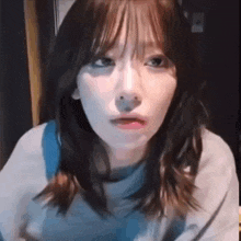 a close up of a woman making a funny face while wearing a blue shirt .
