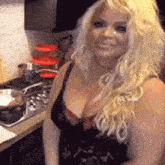 a blonde woman in a black bra is smiling in front of a stove top